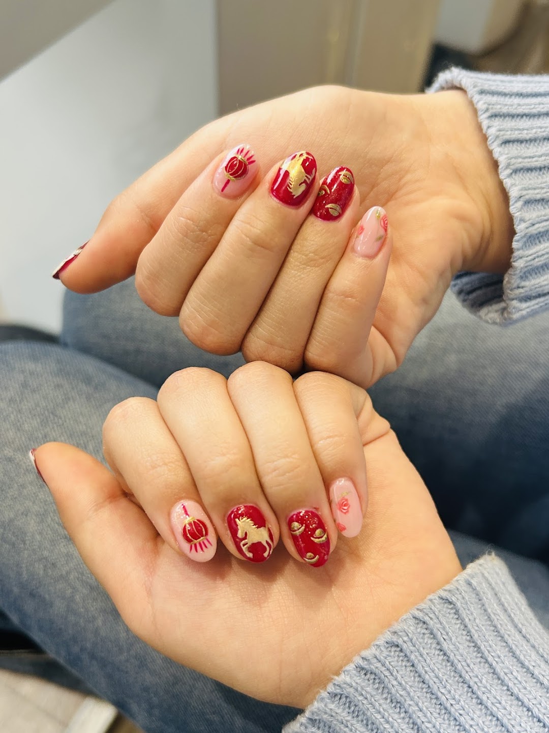 Red and pink decorative nail art with gold accents